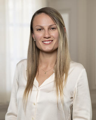 Laura smiles for the camera wearing a white shirt with a white airy background