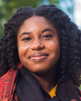 Headshot of Danielle, looking confident and wearing a yellow sweater and a scarf.