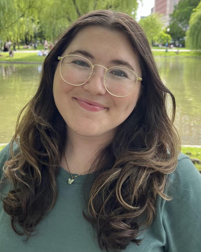 Megan smiles in front of a nature-y green background