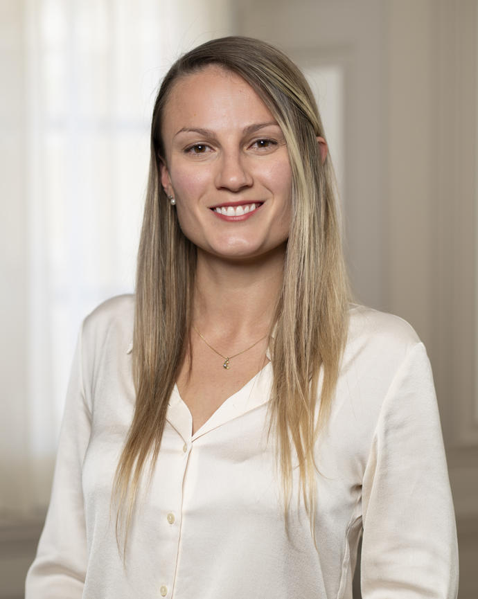 Laura smiles for the camera wearing a white shirt with a white airy background